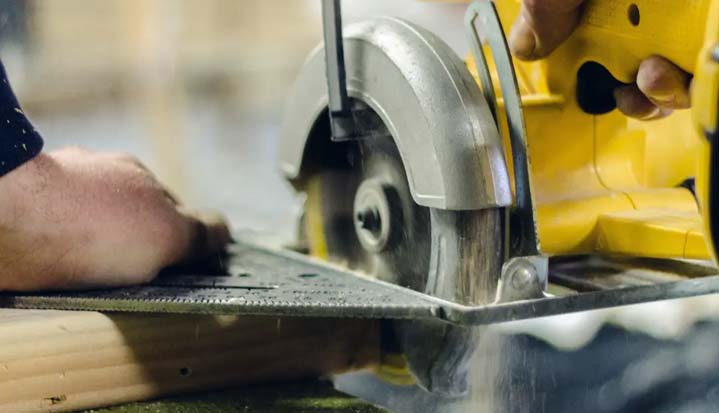 Hombre cortando madera con una sierra circular eléctrica.