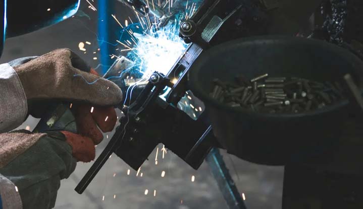 Hombre dándole forma a piezas metálicas.