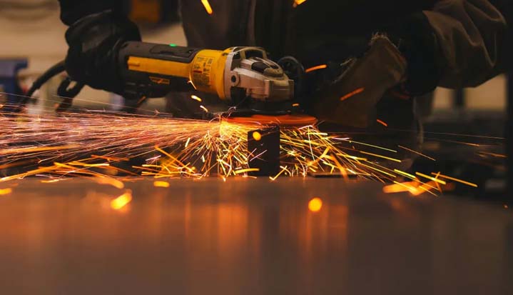 Persona trabajando metal con un esmeril.